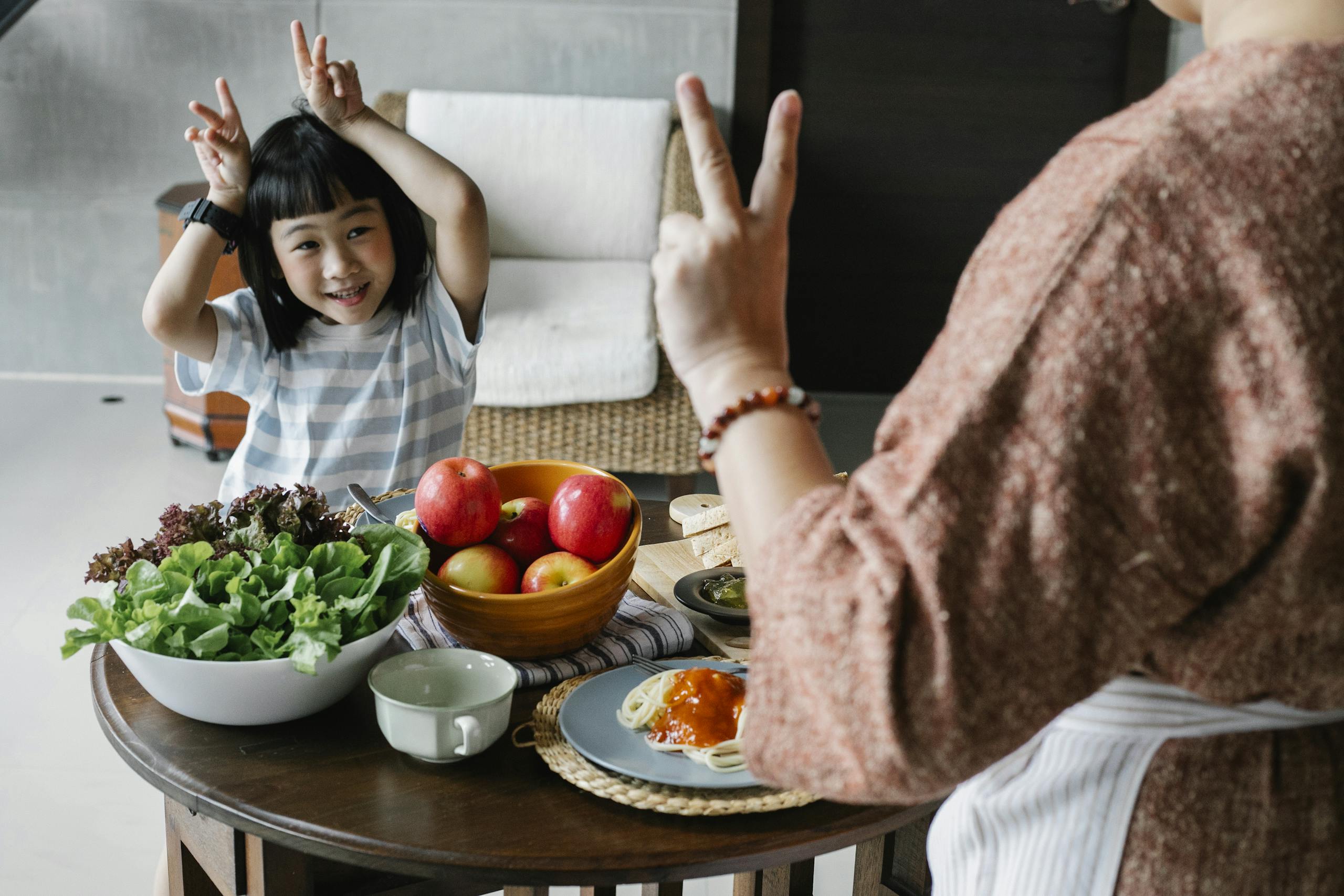 Photo by Alex Green | Motherhues A cheerful child and parent enjoying a healthy meal at home with fresh fruits and vegetables.