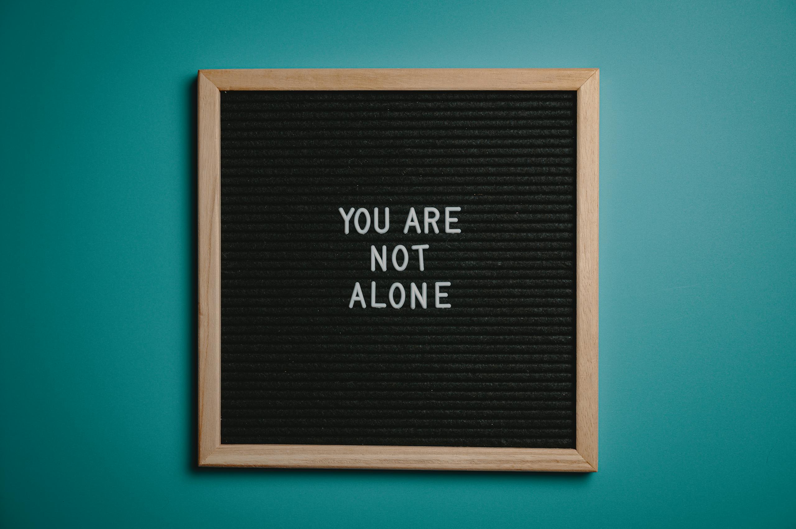 Photo by Brett Sayles | Motherhues A wooden letter board displays a motivational message against a teal background.