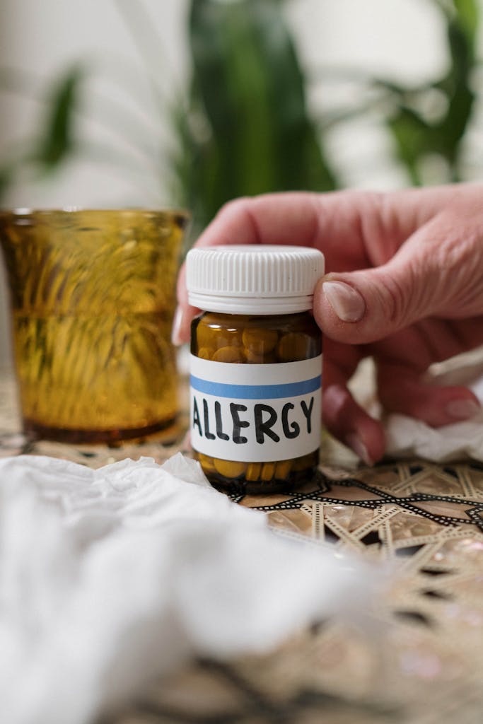 Photo by cottonbro studio | Motherhues Close-up of allergy medication bottle with tissues and amber glass indoors.