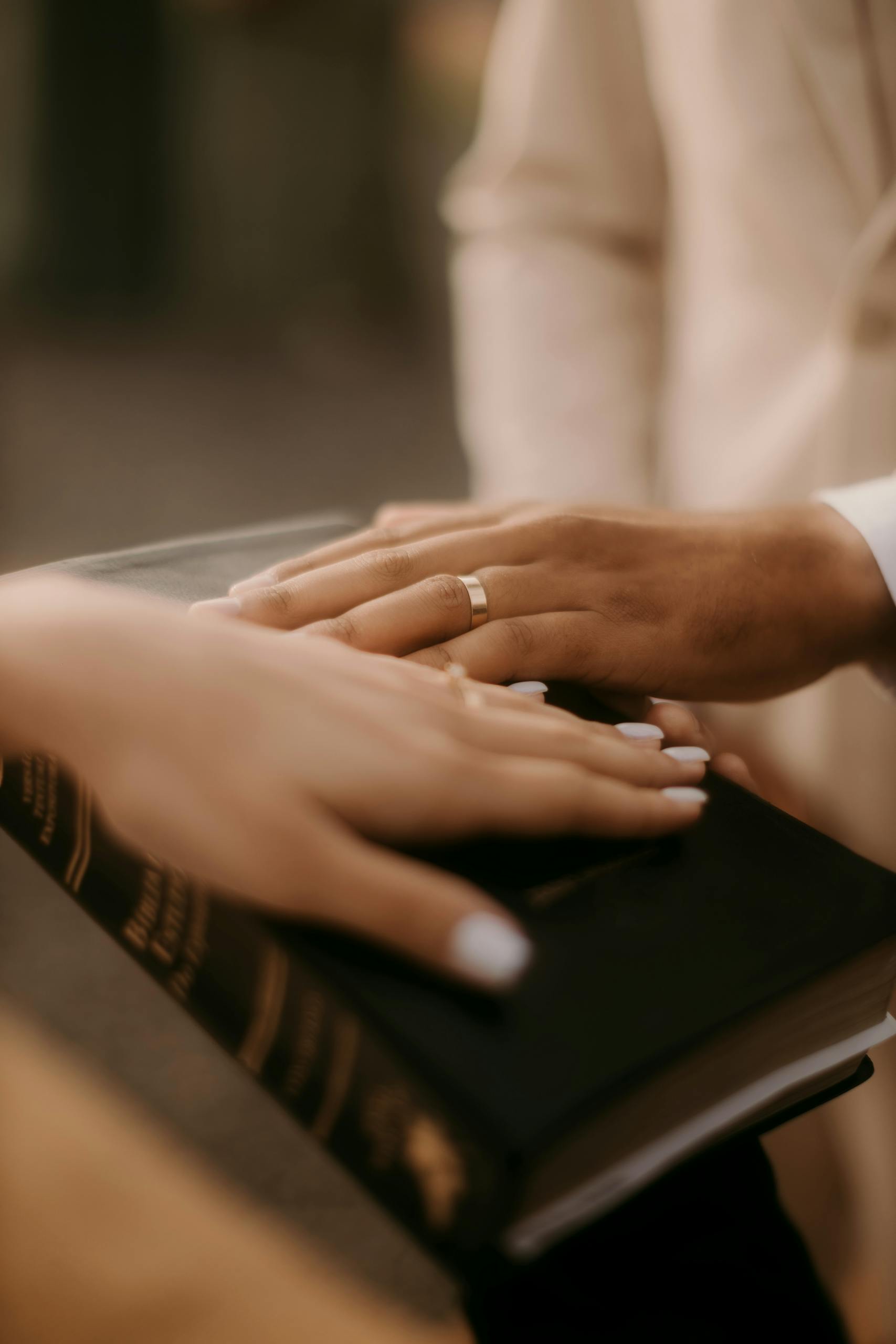 Gentle close-up of hands on Bible, symbolizing unity and commitment.