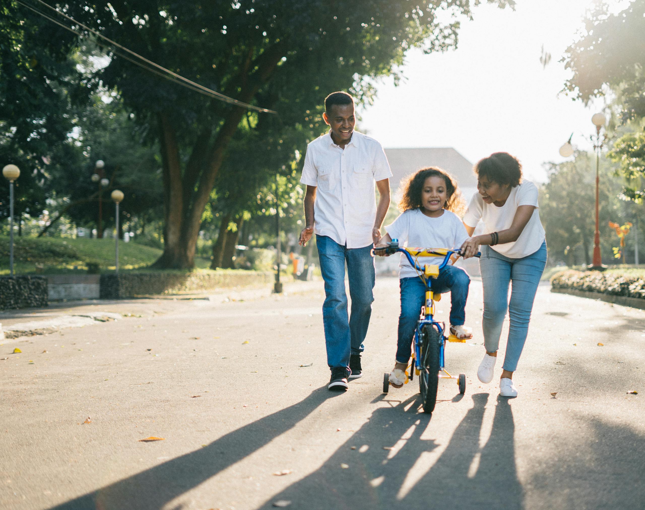 Photo by Agung Pandit Wiguna | Motherhues Happy family teaching their child to cycle on a sunny day outdoors.
