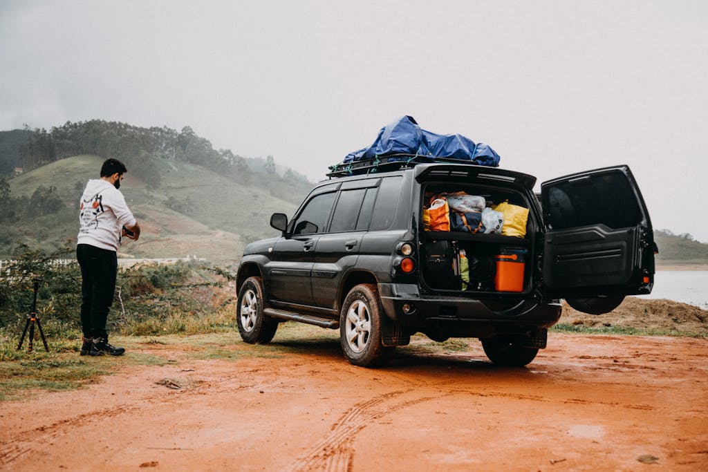 Photo by Matheus Bertelli | Motherhues Man prepares for a foggy countryside adventure trip with a packed SUV.
