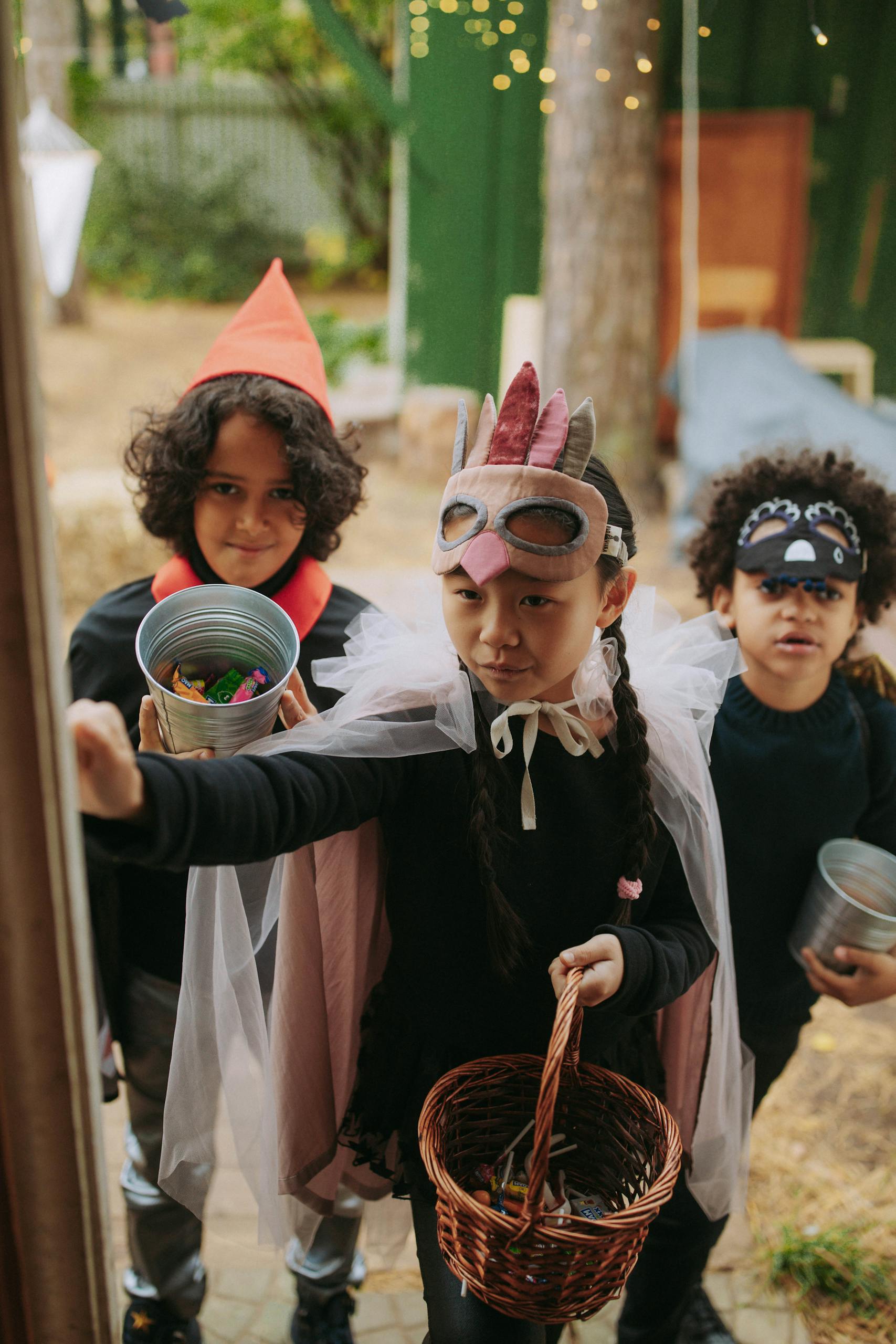 Kids in costumes collecting candy during Halloween trick or treat night.