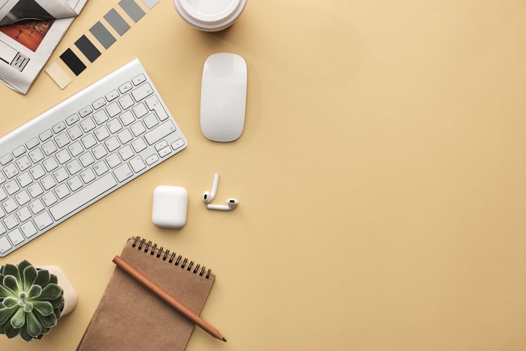 Photo by fauxels | Motherhues A minimalist workspace flat lay with keyboard, mouse, notebook, and succulent on a beige background.