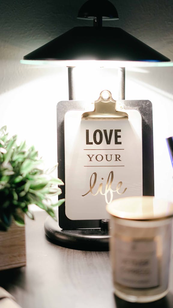 Photo by Natasha Fernandez | Motherhues A warmly lit desk setup featuring a lamp, inspirational clipboard, and decor for a cozy ambiance.