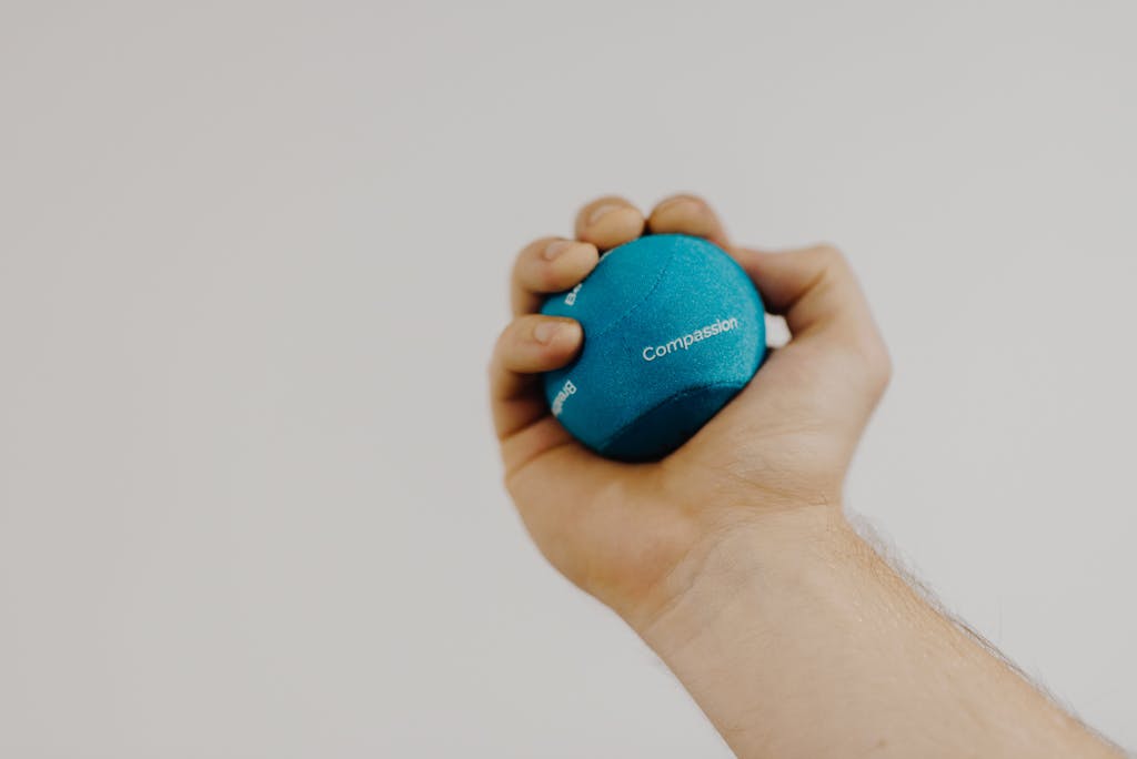 Photo by Anete Lusina | Motherhues Crop unrecognizable male athlete with small rubber ball in hand exercising during recovery process on light background