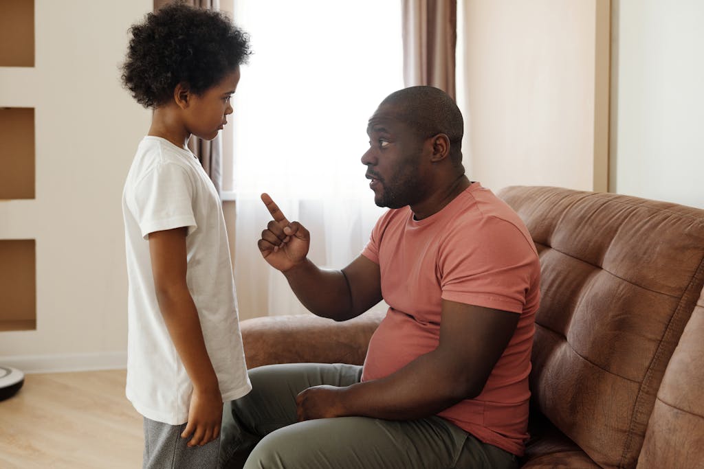 Photo by August de Richelieu | Motherhues Father parenting son engaged in a heartfelt conversation on the sofa, illustrating parenting in a loving family setting.