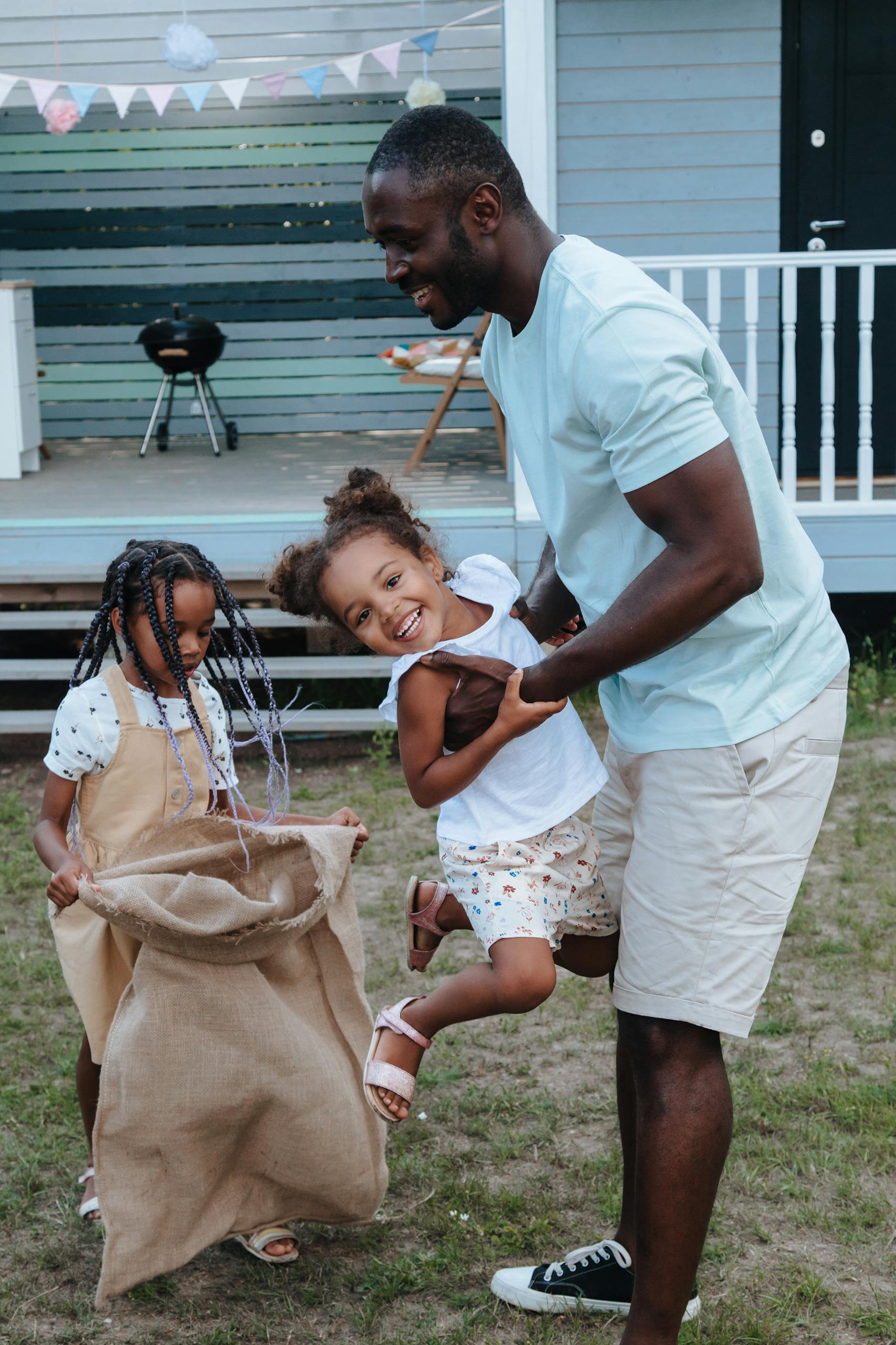 Joyful family moment with father and daughters playing outdoors in the yard.