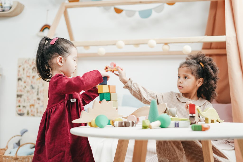 Photo by cottonbro studio | Motherhues Two young girls (kids) enjoying playtime with wooden toys indoors in a warm, colorful playroom.