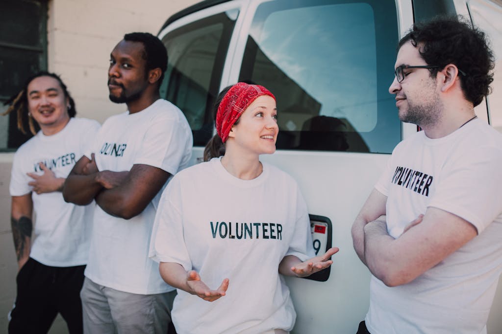 Photo by RDNE Stock project | Motherhues Four volunteers interacting by a van, promoting community service and involvement.