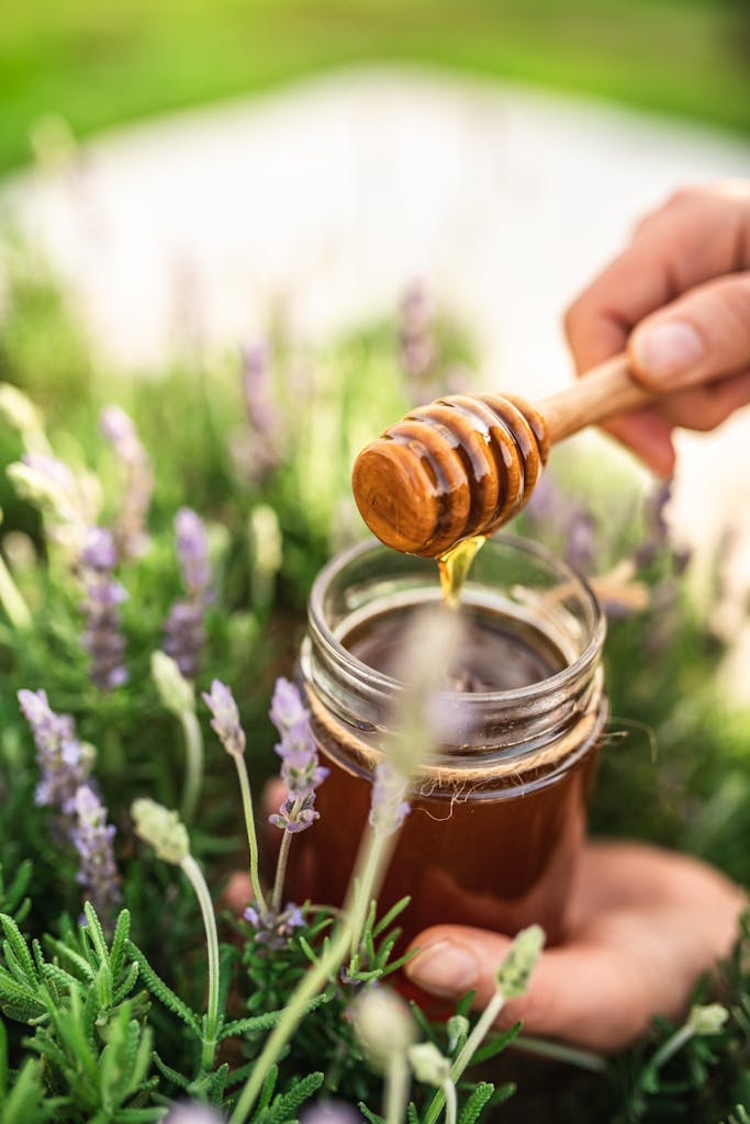 Photo by lengliz hedi | Motherhues Honey dipper with jar in a lush spring garden setting with lavender flowers.