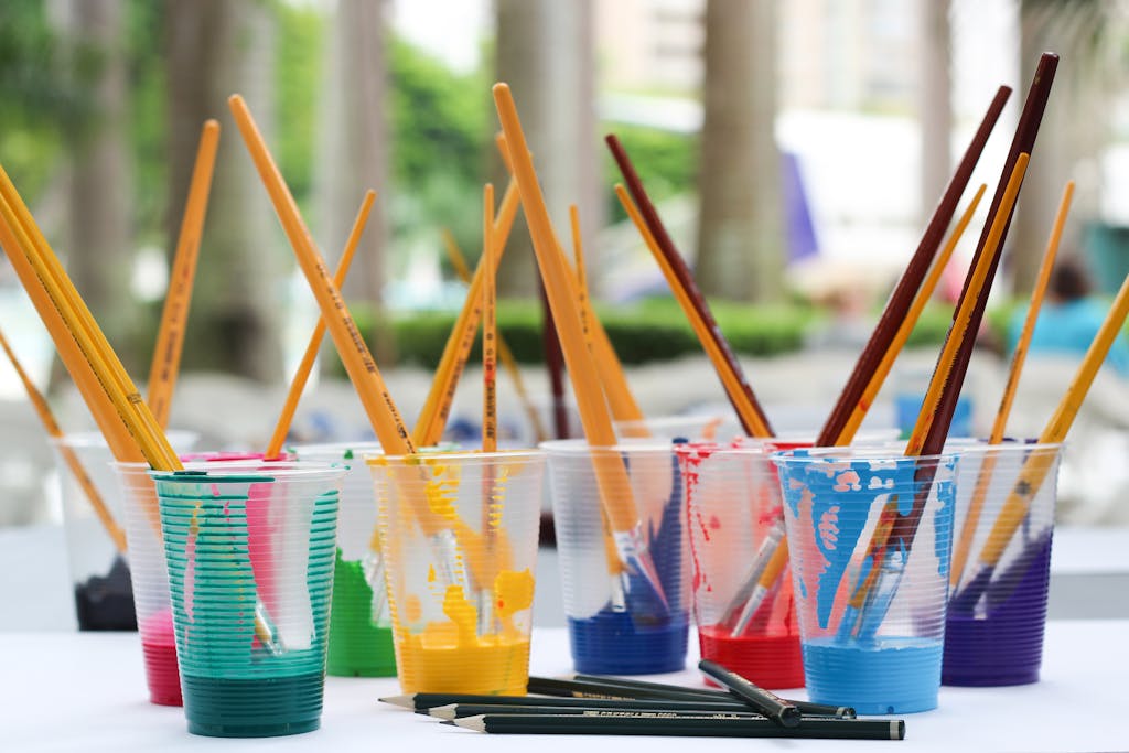 Photo by Jadson Thomas | Motherhues Vibrant paint brushes and pencils in plastic cups for arts and crafts.